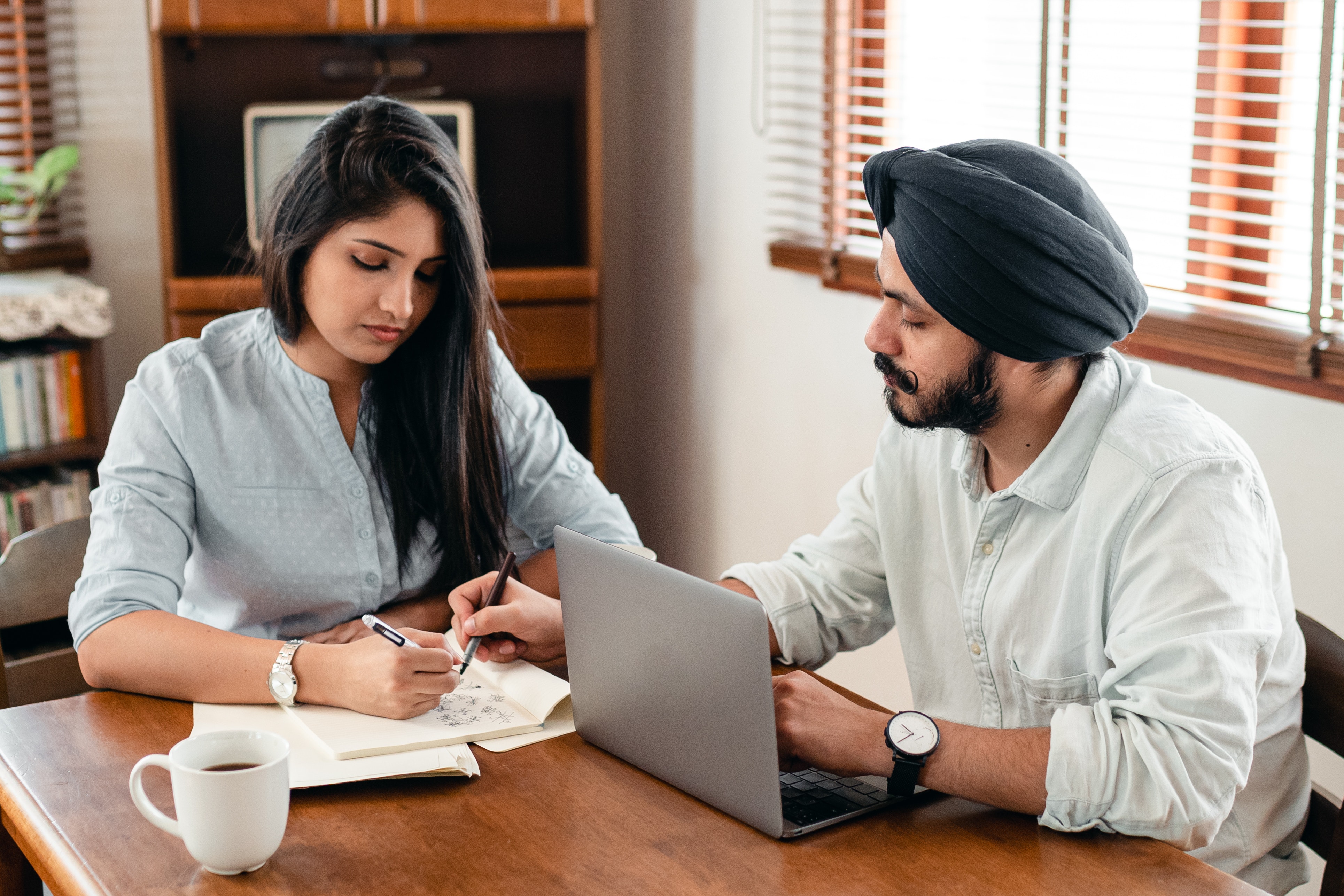 young-ethnic-spouses-with-notepad-and-laptop-at-home-4308100
